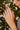 Close-up of a hand wearing two diamond rings with a blurred green leafy background